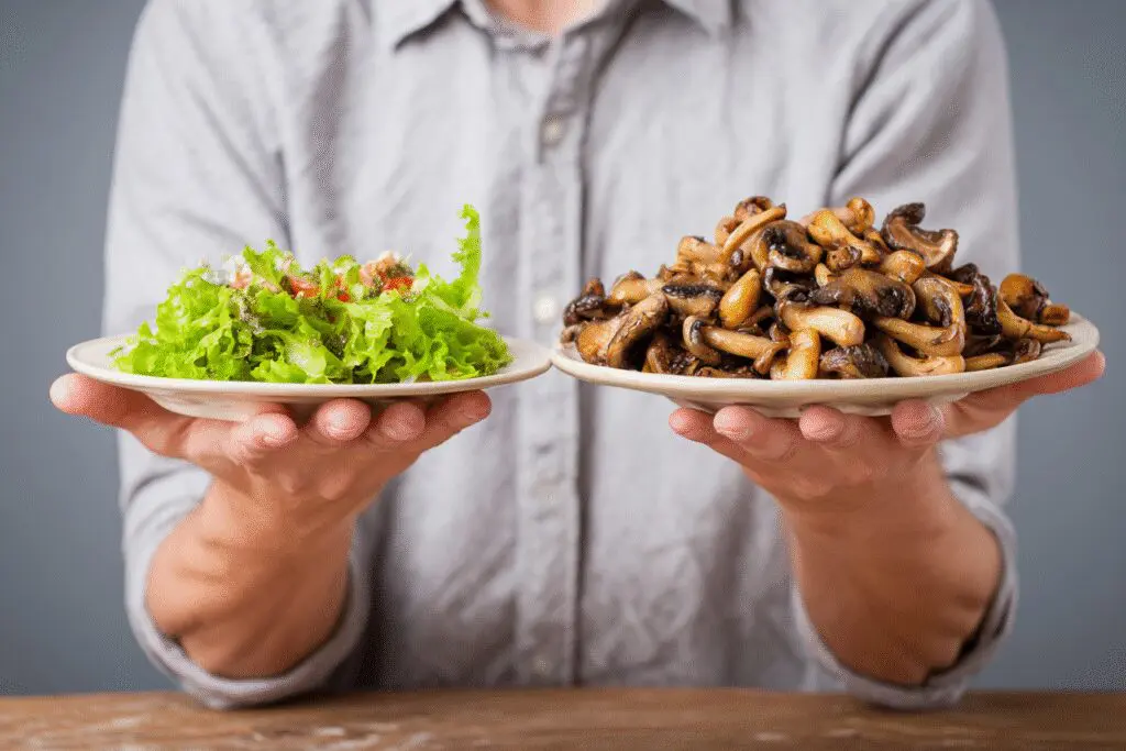 A person choosing a plate of mushrooms over a small salad illustrating the answer to the FAQ on are mushrooms good for weight loss A person choosing a plate of mushrooms over a small salad illustrating the answer to the FAQ on are mushrooms good for weight loss