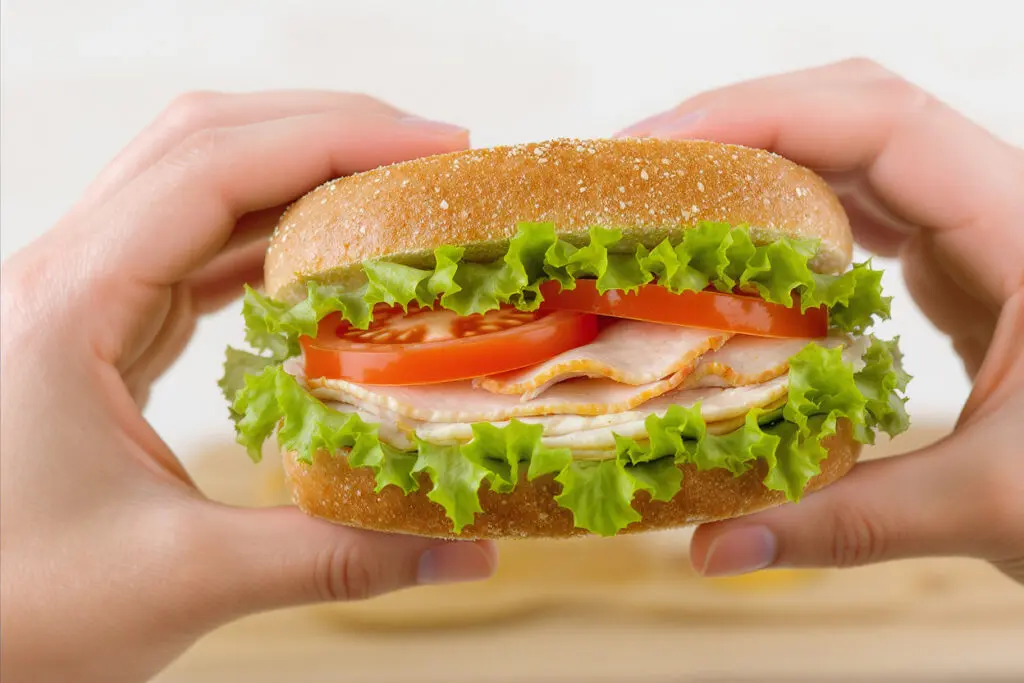 a healthy sandwich being made with whole wheat bread lean protein and fresh vegetables highlighting its role in a fiber-rich weight loss diet